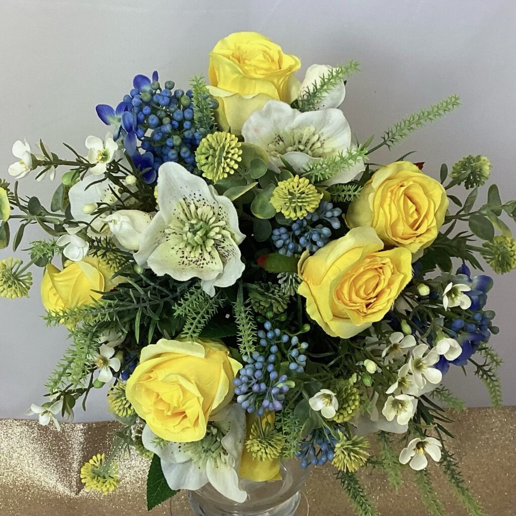 artificial silk flower bridal bouquet. hand tied posy style. blues, yellows, ivory. inc hellebores, roses, berry, wax flower, globe thistle & spikey greenery